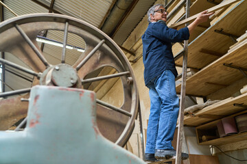 Experienced worker organizing wood shelves in a busy lumberyard