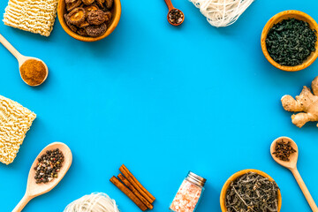 Chinese and Japanese food cooking with ginger, spices and noodles frame on blue background top view...