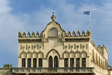 Fototapeta premium Close-up of a historic building in Rhodes, Greece, façade displays decorative arched windows, intricate stucco reliefs, circular motifs, and crenellated roof details