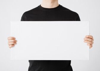 Person in Black Shirt Holding a Blank White Canvas, Ideal for Adding Text or Graphics, Perfect for...