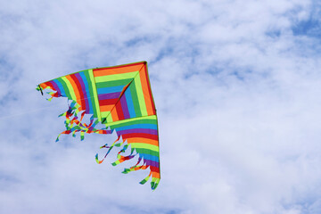 Bright kite against the cloudy sky. Toy for children and adults. Outdoor activities. Colorful kite...