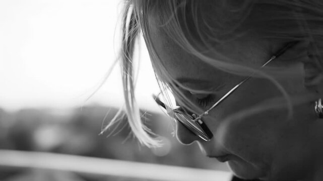 A woman with glasses looks down as she flips through the pages of a booklet in front of her