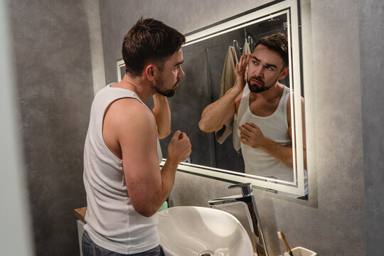 Man Examining Skin in Mirror During Daily Grooming Routine