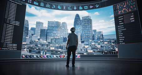 Young Urban Planner, Wearing a VR Headset, Shapes a Futuristic Urban Development. Big Digital Panorama Screen Visualizes a Cityscape, Responding to the Engineer's Design Choice