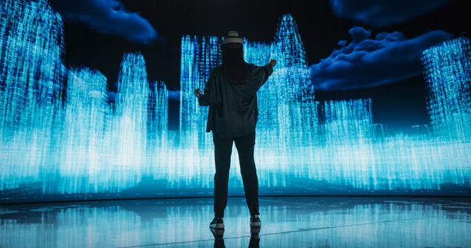 Female Urban Designer Immersed in Virtual Reality, Reimagines a Futuristic City. Virtual Production LED Wall Displays a Cityscape Polygon Model that is Transformed and Manipulated on Screen
