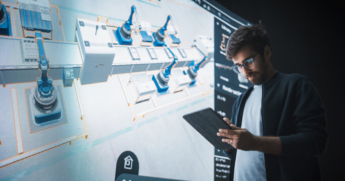 Indian Robotics Specialist Programs a Group of Robotic Arms with the Help of a Tablet Computer. Specialist Creates and Programs the Assembly Line Online, Optimizing Production and Improving Efficiency