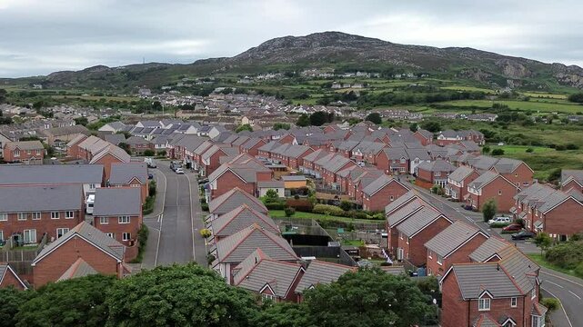 Aerial view across modern red brick housing neighbourhood under Holyhead mountain in Wales