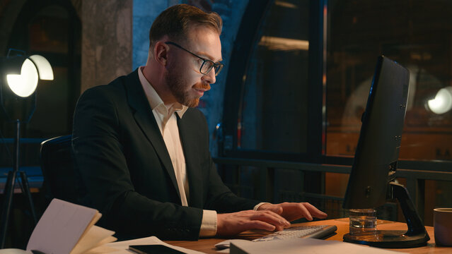 Caucasian businessman busy concentrated guy with papers documents at table workplace work hard lot of tasks job business man male working computer at night overtime office late time deadline overwork - Powered by Adobe