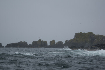 rugged shores of isle of may with cliffs in a stormy see
