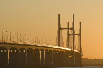 Second Severn crossing (Prince of Wales bridge) is silhouetted against a warm, golden sunrise sky