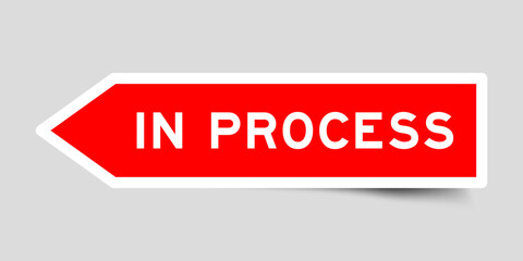 Red color arrow shape sticker label with word in process on gray background