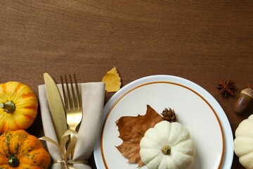 Rustic holiday table setup. Top view with plates, cutlery and autumn decorations. Empty space for...