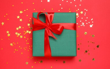 Beautiful gift box with confetti on bright red background, top view