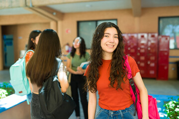Cute High school student standing next to her friends in hallway