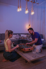 Happy Couple Playing Tabletop Foosball Together in Cozy Living Room