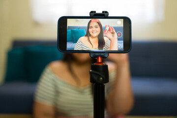 Content creator recording makeup tutorial video with smartphone on tripod