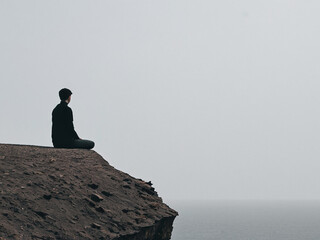 Contemplative Man Sitting on Cliff Edge, Ocean View, Peaceful Solitude