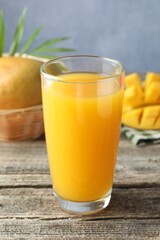 Tasty mango juice in glass and fresh fruits on wooden table, closeup