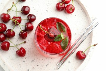 Tasty cherry soda with ice cubes, mint and berries on white wooden table, flat lay