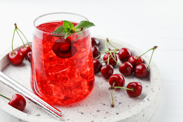 Tasty cherry soda with ice cubes, mint and berries on white wooden table, closeup