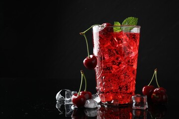 Tasty cherry soda with ice cubes, berries and mint in glass on black background, closeup. Space for...