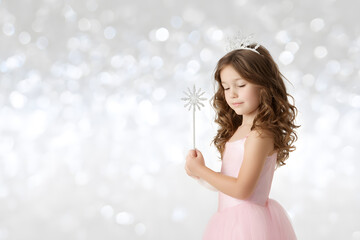 Young girl dressed as fairy with tiara and magic wand, white background with sparkles.
