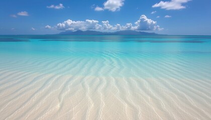 Fototapeta premium A serene tropical beach with crystal-clear turquoise water and a bright blue sky. The view is stunning with fluffy clouds overhead.