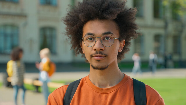 Portrait outdoors African American ethnic student guy male man in glasses education studying university academy college learning knowledge in city posing talking friends women background bullying