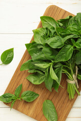 Green basil herb on cutting board on white background. Vertical photo