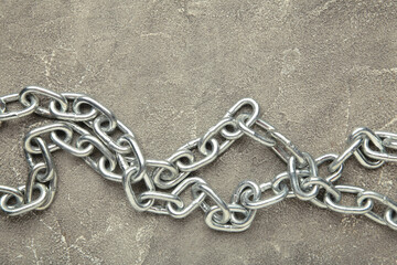 Iron chain of light metal on grey concrete background.