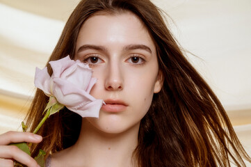 Portrait, brunette with clear skin with pale purple rose, near lips