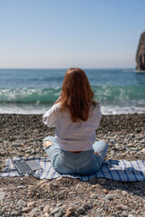Beach Laptop Woman works remotely on pebble beach during the day, enjoying the seaside view.