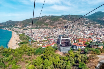 A scenic cable car ride in Alanya, Turkey, reveals breathtaking views of the city and Kleopatra Beach. The Mediterranean coastline and lush greenery create a captivating landscape