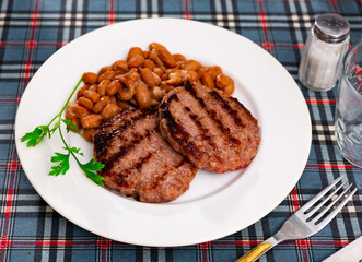 Plate contains light side dish of stewed vegetables - red kidney beans complemented by meat patty, flat beef cutlet . Diet menus, vegetable appetizer.