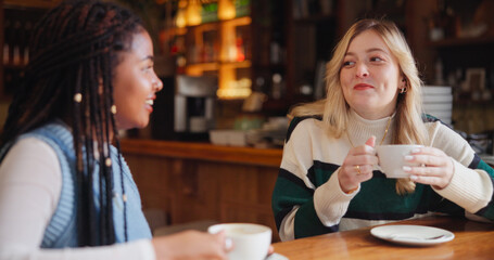 Coffee shop, talking and women with drink in conversation for hangout, reunion and bonding. Restaurant, friends and people with beverage, discussion and gossip for relationship, social chat and relax