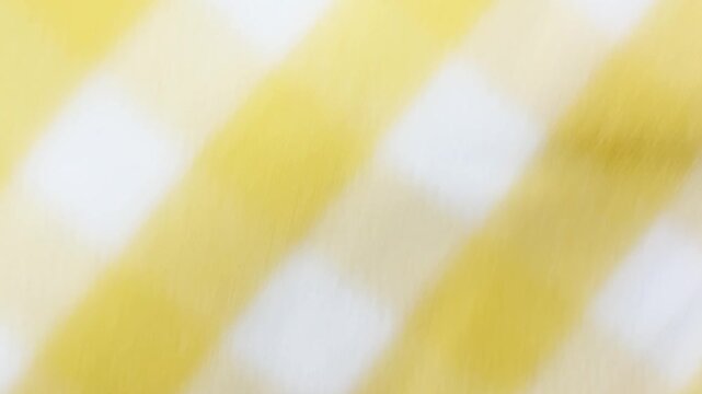 Close-up of bright yellow and white checkered fabric with diagonal gingham pattern. A cheerful and sunny textile background loop, evoking summer and warmth