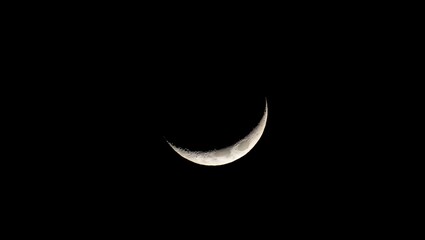 Moon, crescent, astronomy: A luminous thin crescent moon glows brightly against the deep black sky, revealing intricate craters, mountains, and maria in high-resolution detail, highlighted by Earthshi