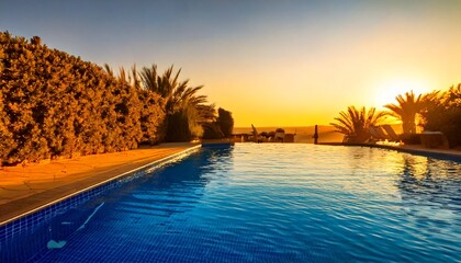Water reflects the warm yellow sunset sky beside a peaceful swimming pool, evoking a calm vacation atmosphere, perfect for relaxation, unwinding, and enjoying tranquil moments in a serene environment.