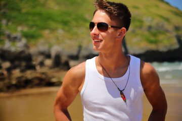 Young guy in sunglasses on the beach, casual teenager style, summer lifestyle