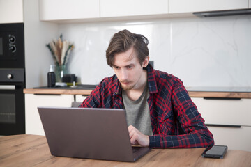 a young man  concentrate our energy and using a laptop, connecting to the Internet in the kitchen...