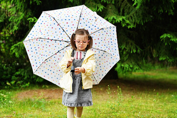 Kid girl with umbrella in yellow boots