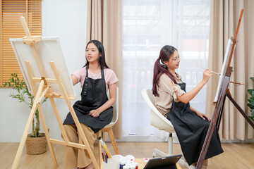 Two young asian woman artist painting on canvas. Female artist drawing with inspiration at home