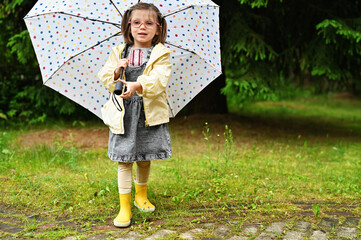 Kid girl with umbrella in yellow boots