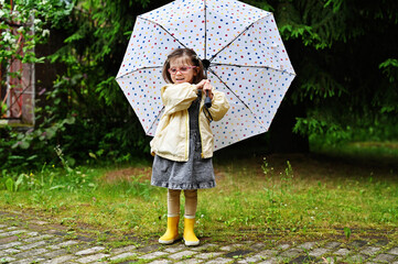 Kid girl with umbrella in yellow boots