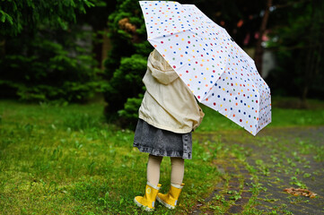 Kid girl with umbrella in yellow boots