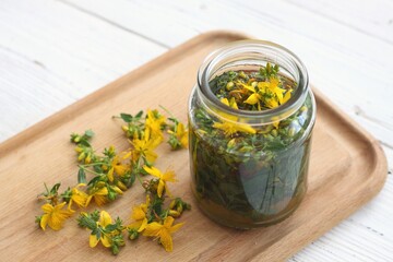 Tincture from Hypericum perforatum commonly known as St John's wort. Tincture  with fresh yellow St John's wort flowers inside and on the cutting board. Traditional herbal medicine.
