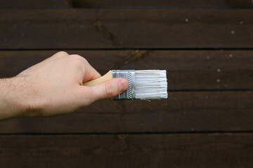 Construction brush with white paint on a wooden background.