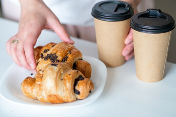 Woman holding croissant and coffee cup at home, concept: enjoying simple pleasures