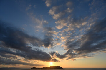 夕日の沈む海と島影と雲の風景