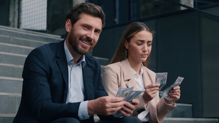 Two business man and woman in city counting money cash happy smile rich male and sad frustrated female businessman with businesswoman gender inequality financial unequal discrimination sexism at work